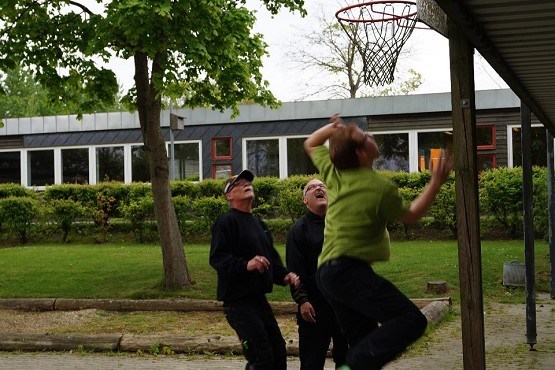 Tre personer, der leger med et basketballnet.