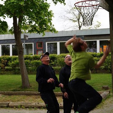 Tre personer, der leger med et basketballnet.