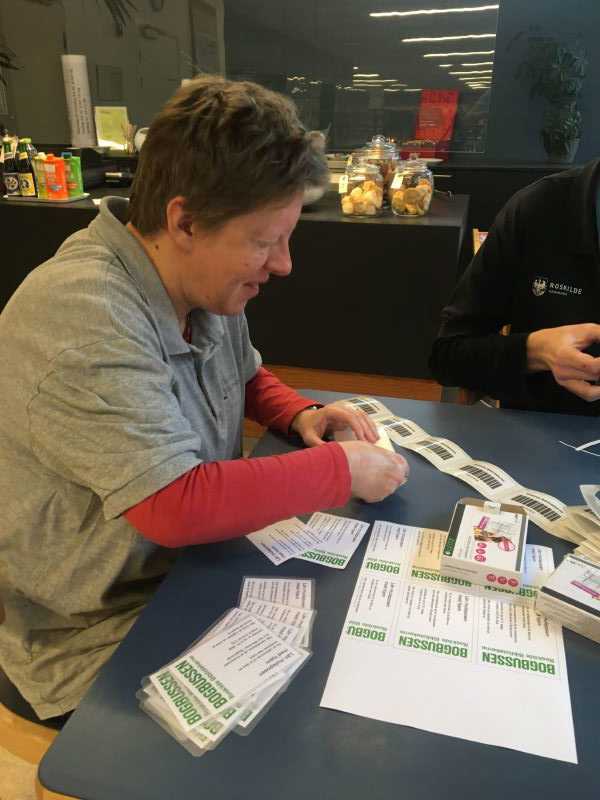 Mennesker sætter mærkater med "Bogbussen" på sedler.