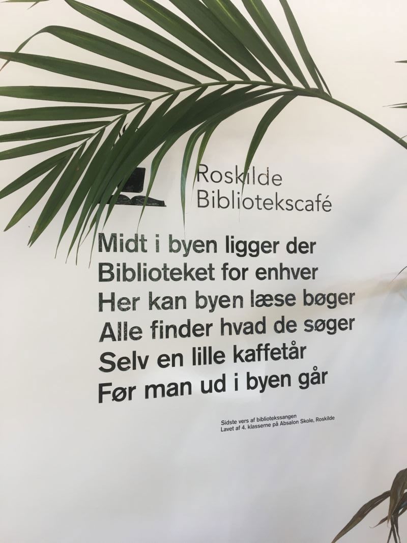 Klistermærker på en væg på bibliotekscaféen. Det er første vers i en sang.