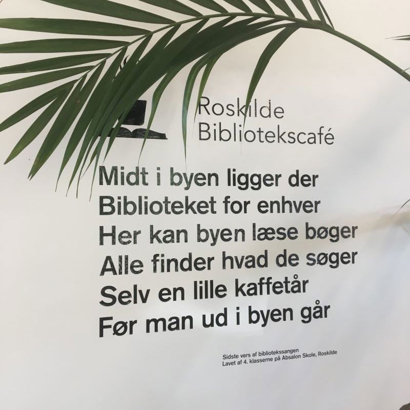 Klistermærker på en væg på bibliotekscaféen. Det er første vers i en sang.