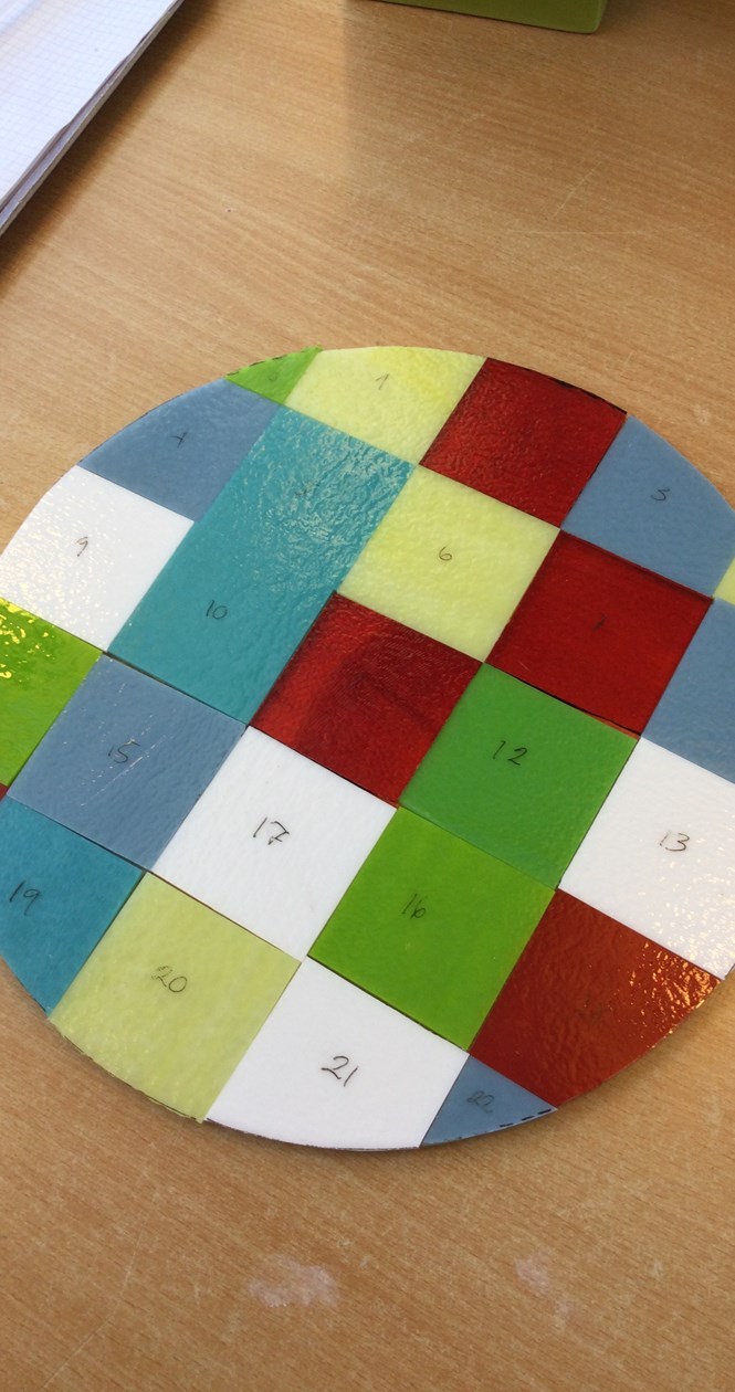 Viser fremstillingen af rund glasplade med flere forskellige farver. Det er skabt af forskellige, små plader med numre på.