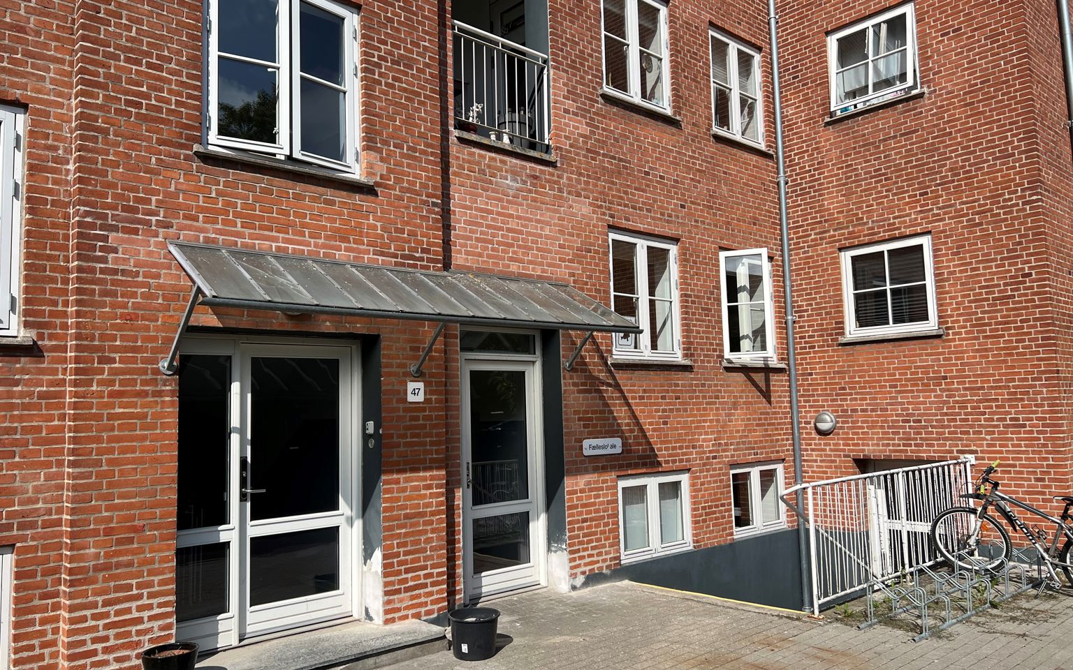 En rød murstensbygning med åbne vinduer. En kvinde kigger ud af vinduet og vinker.