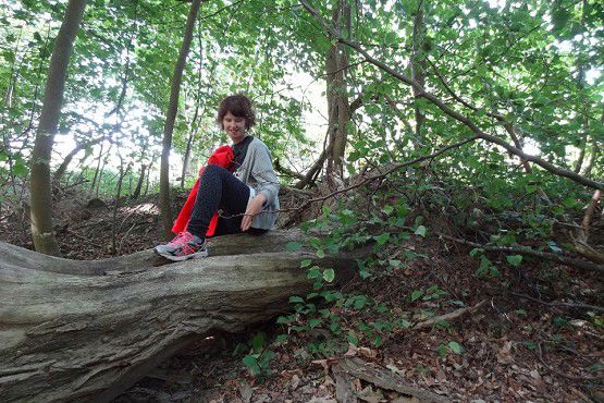 Person sidder på et træ, der er væltet, i naturen.