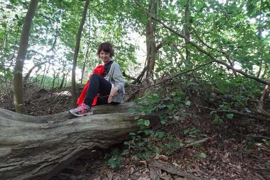 Person sidder på et træ, der er væltet, i naturen.