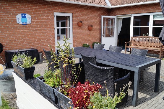 Bostedet Hørhus set udefra. Der er nogle terrassemøbler og flotte planter. 