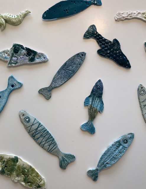 Fisk i keramik. Der er forskellige slags fisk, og de er alle en form for blå eller grøn.