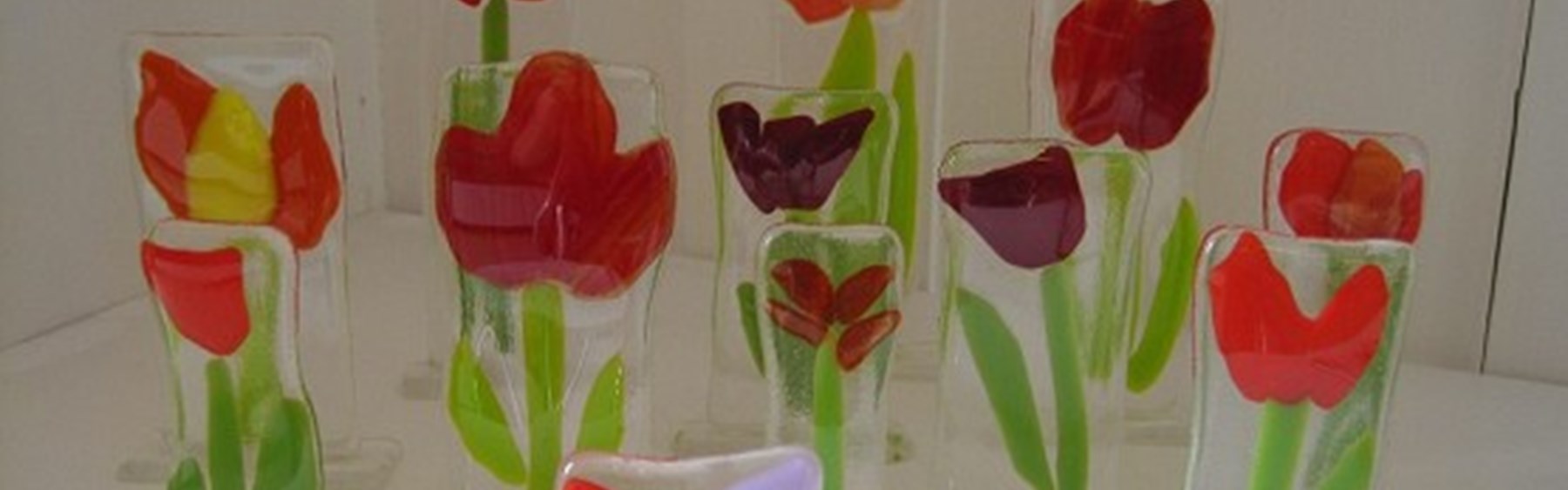 Fint kunst lavet af glas. Det forestiller blomster. De fleste er røde tulipaner.