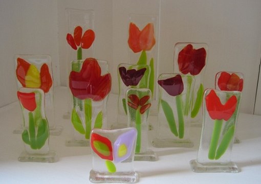 Fint kunst lavet af glas. Det forestiller blomster. De fleste er røde tulipaner.