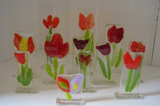Fint kunst lavet af glas. Det forestiller blomster. De fleste er røde tulipaner.
